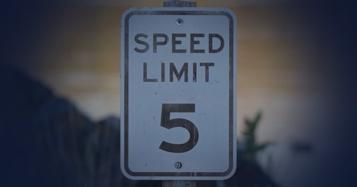 a speed limit sign sitting next to a body of water